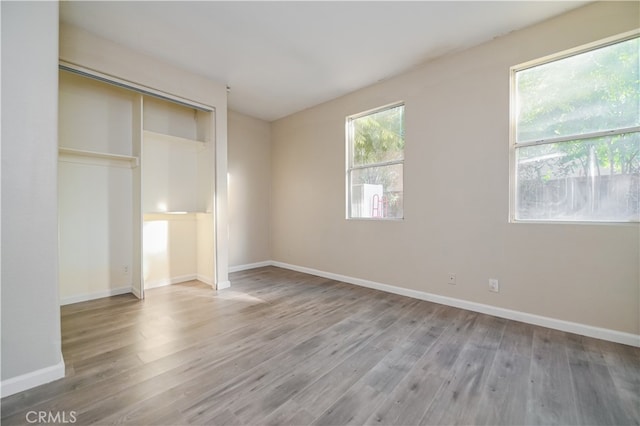 unfurnished bedroom featuring a closet, multiple windows, and hardwood / wood-style flooring