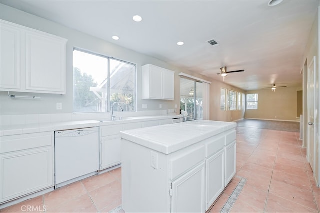 kitchen with tile countertops, dishwasher, white cabinets, and a center island