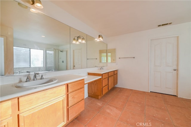 bathroom with vanity, an inviting chandelier, a shower with shower door, and tile patterned flooring