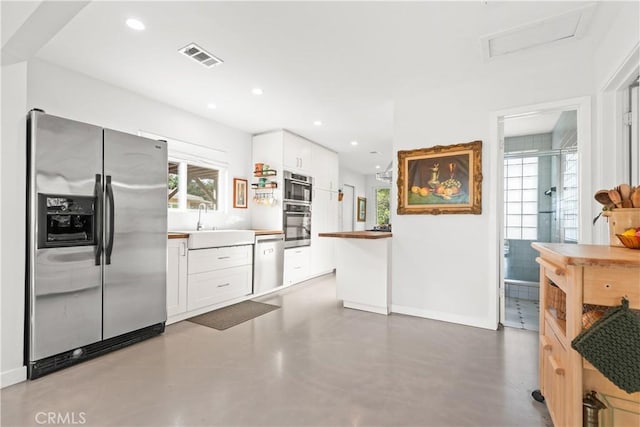 kitchen with concrete flooring, appliances with stainless steel finishes, white cabinetry, and sink