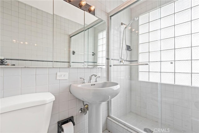 bathroom with toilet, plenty of natural light, tile walls, and walk in shower