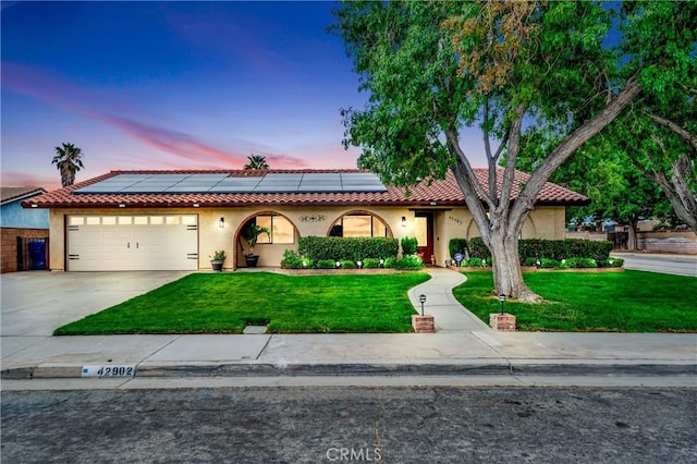 view of front of house with a lawn, a garage, and solar panels