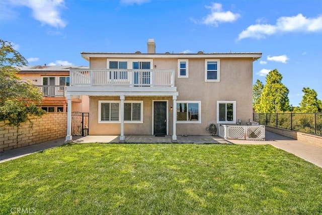 back of house with a lawn, a patio area, and a balcony