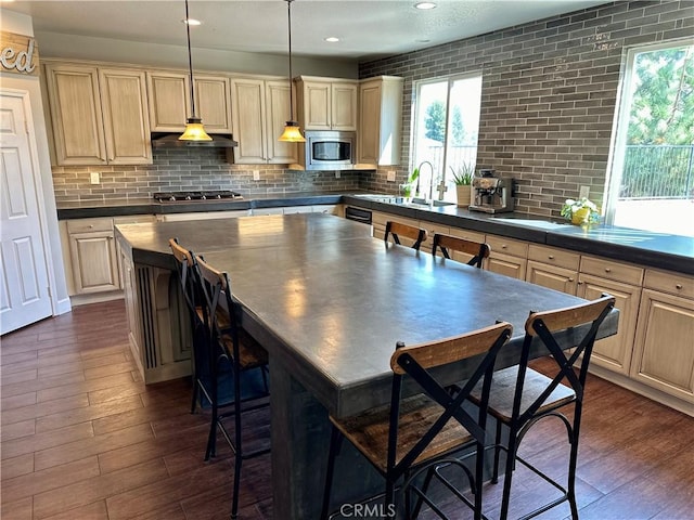 kitchen with pendant lighting, a center island, sink, dark hardwood / wood-style floors, and appliances with stainless steel finishes