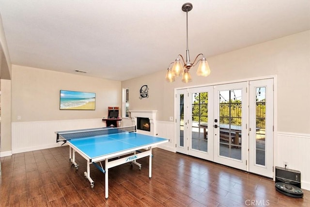 recreation room with a notable chandelier, dark wood-type flooring, and french doors