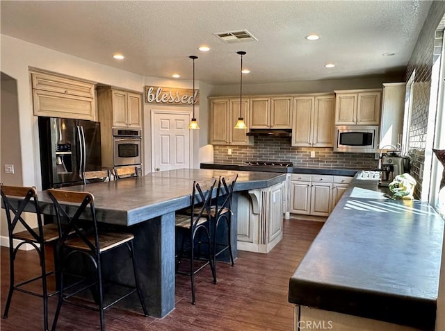 kitchen with pendant lighting, a center island, a kitchen breakfast bar, dark hardwood / wood-style floors, and appliances with stainless steel finishes