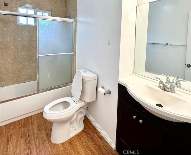 full bathroom with toilet, vanity, bath / shower combo with glass door, and hardwood / wood-style flooring