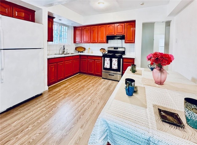 kitchen featuring white refrigerator, stainless steel stove, backsplash, and sink