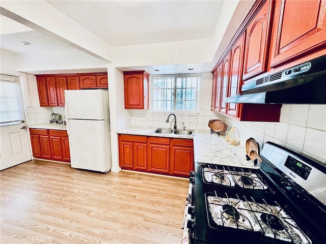 kitchen featuring white fridge, black range with gas cooktop, a wealth of natural light, and sink