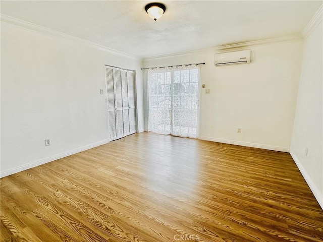 unfurnished room featuring hardwood / wood-style flooring, an AC wall unit, and crown molding