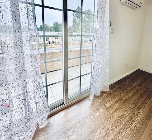 doorway to outside with hardwood / wood-style floors and a wall unit AC