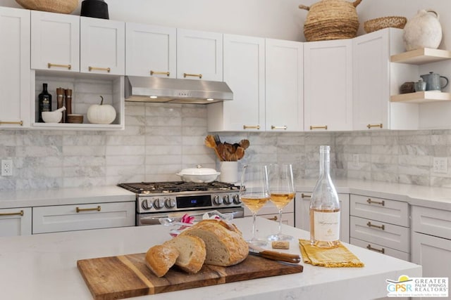 kitchen with white cabinets, tasteful backsplash, high end stainless steel range oven, and light stone counters