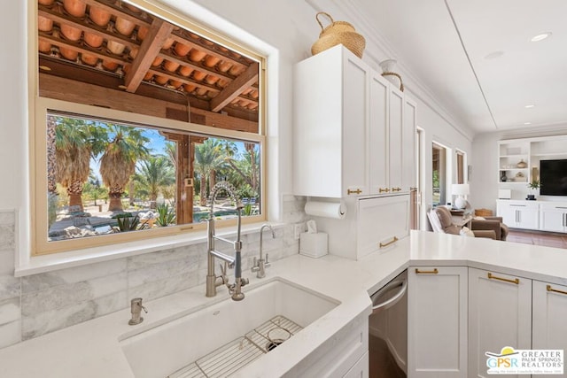 kitchen with backsplash, dishwasher, sink, and white cabinets