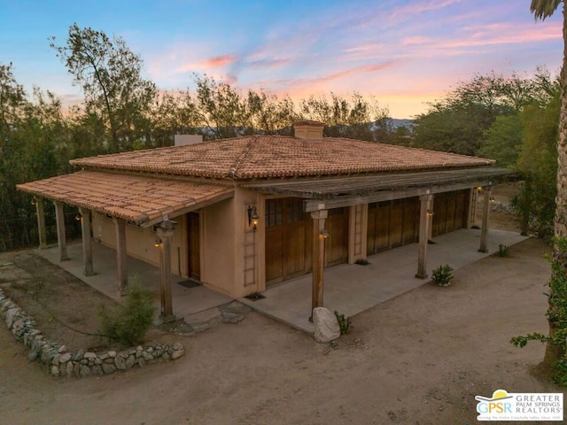 back house at dusk featuring an outdoor structure