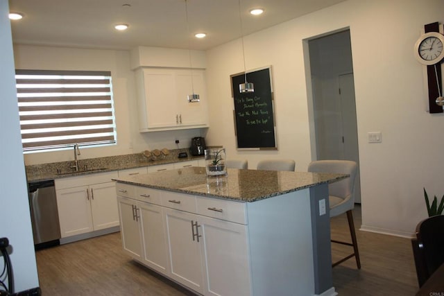 kitchen featuring sink, stainless steel dishwasher, a kitchen island, a kitchen bar, and white cabinetry