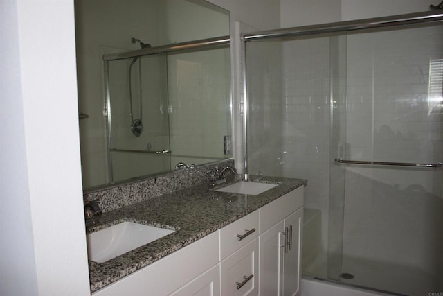 bathroom featuring a shower with door and vanity