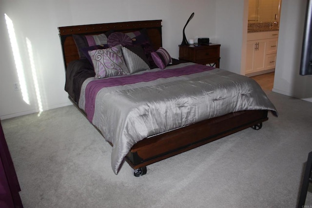 bedroom featuring light colored carpet and ensuite bath