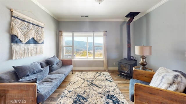 living room with hardwood / wood-style flooring, a mountain view, crown molding, and a wood stove