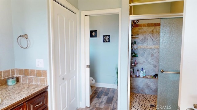 bathroom with vanity, tiled shower, hardwood / wood-style floors, and toilet