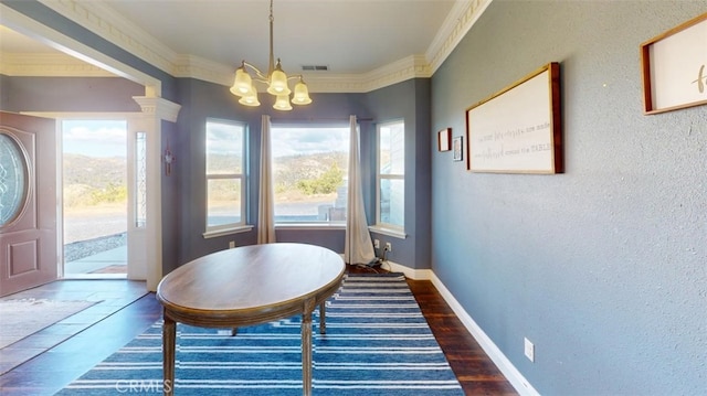 dining room featuring an inviting chandelier, ornamental molding, and dark hardwood / wood-style flooring