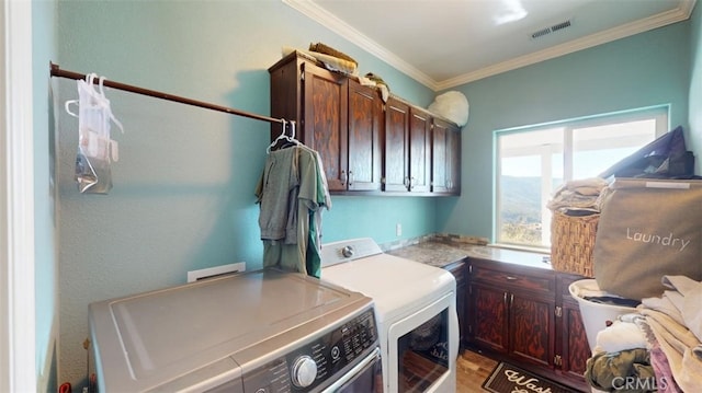 laundry room featuring cabinets, crown molding, and washer and clothes dryer