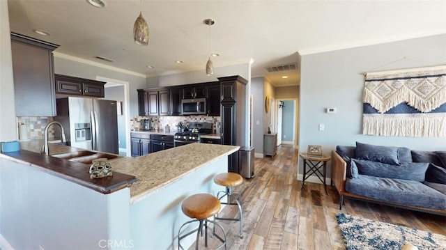 kitchen featuring a kitchen breakfast bar, appliances with stainless steel finishes, kitchen peninsula, and light wood-type flooring