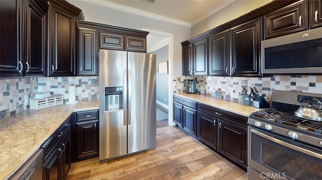 kitchen with backsplash, appliances with stainless steel finishes, light stone countertops, light hardwood / wood-style flooring, and ornamental molding