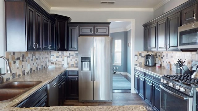 kitchen featuring stainless steel appliances, ornamental molding, sink, and tasteful backsplash