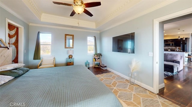 bedroom with multiple windows, hardwood / wood-style flooring, and a tray ceiling