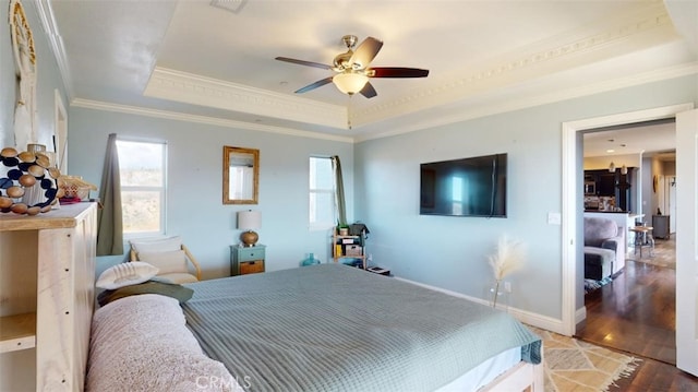 bedroom featuring ornamental molding, hardwood / wood-style floors, ceiling fan, and a raised ceiling