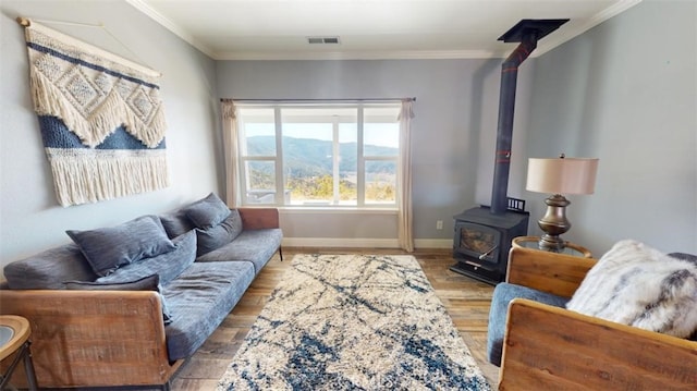 living room with a mountain view, hardwood / wood-style flooring, a wood stove, and crown molding