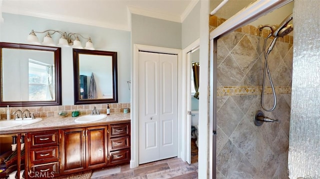 bathroom featuring decorative backsplash, toilet, ornamental molding, vanity, and a tile shower