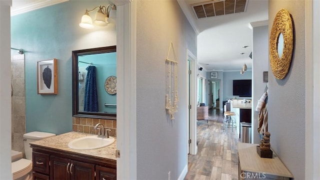 bathroom featuring toilet, ornamental molding, hardwood / wood-style flooring, and vanity