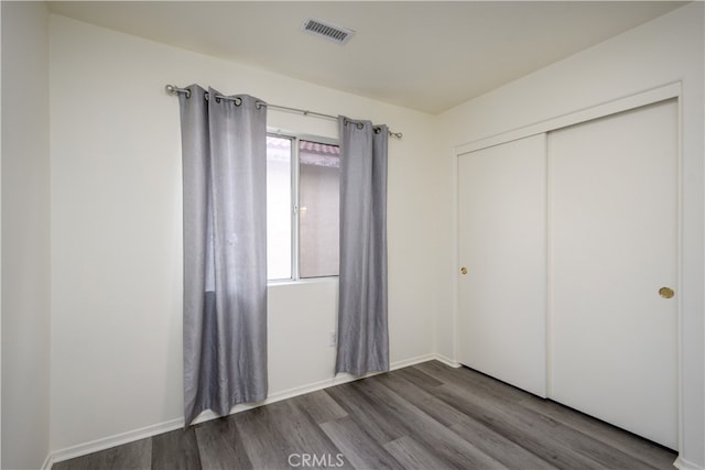 unfurnished bedroom featuring wood-type flooring and a closet