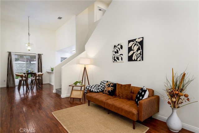 living room with a towering ceiling and dark hardwood / wood-style flooring