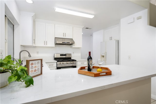 kitchen with extractor fan, white fridge with ice dispenser, kitchen peninsula, stainless steel gas range, and white cabinets