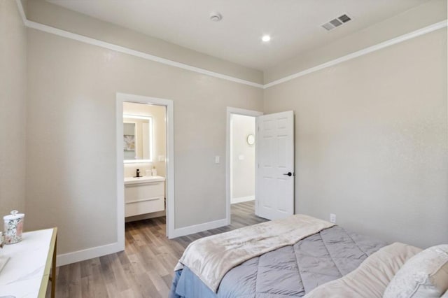 bedroom featuring light hardwood / wood-style flooring and connected bathroom