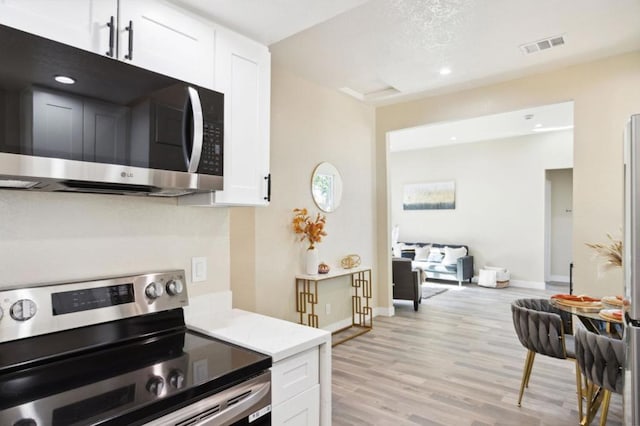 kitchen featuring white cabinetry, light hardwood / wood-style flooring, and appliances with stainless steel finishes