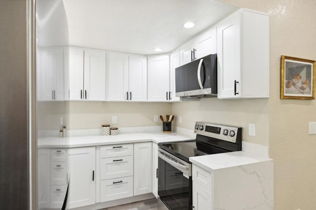 kitchen with light wood-type flooring, white cabinetry, light stone countertops, and stainless steel electric range