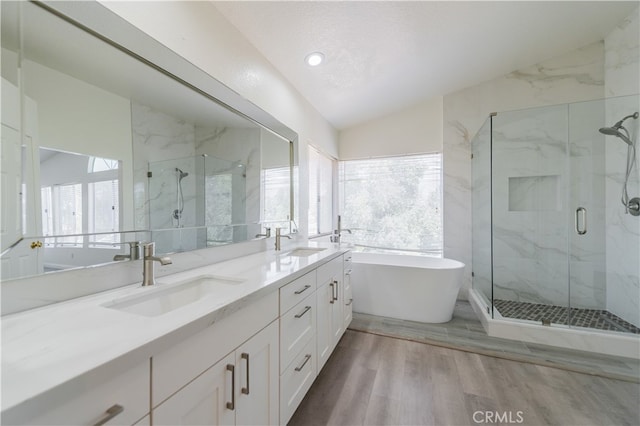 bathroom featuring lofted ceiling, wood-type flooring, vanity, shower with separate bathtub, and a textured ceiling