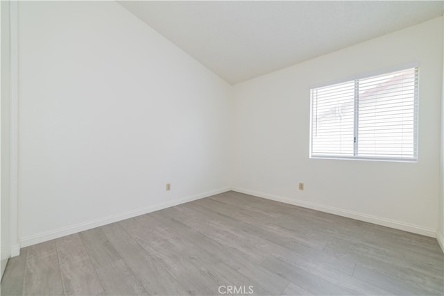 unfurnished room featuring vaulted ceiling and light wood-type flooring