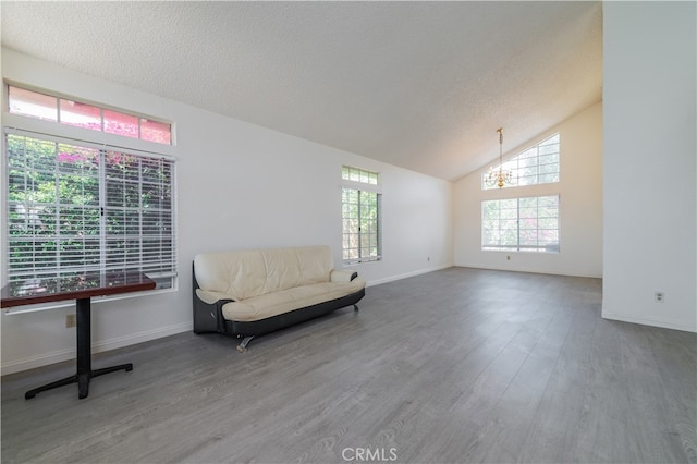 sitting room with hardwood / wood-style floors, a chandelier, a textured ceiling, and vaulted ceiling