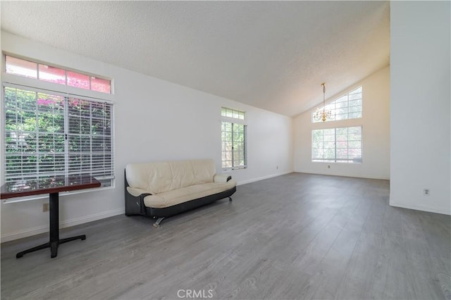 sitting room featuring an inviting chandelier, vaulted ceiling, wood finished floors, and baseboards