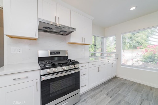 kitchen featuring stainless steel gas range, recessed lighting, under cabinet range hood, light countertops, and white cabinets