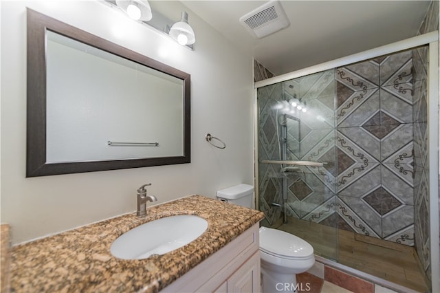 bathroom with toilet, vanity, and a shower with door