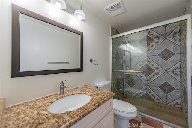 bathroom with toilet, visible vents, a shower stall, and vanity