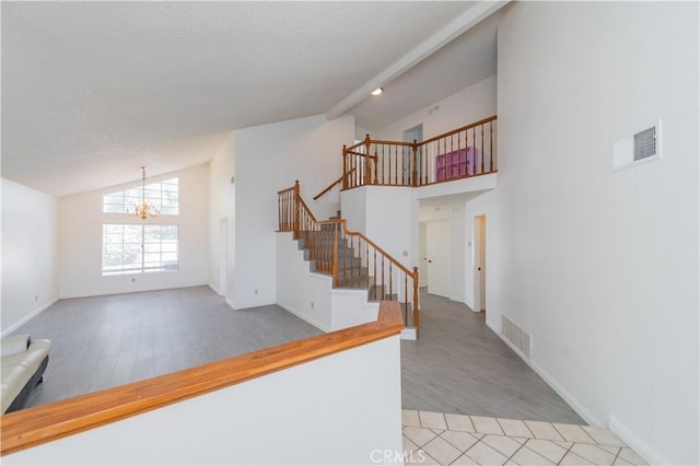 interior space featuring visible vents, lofted ceiling with beams, wood finished floors, a chandelier, and stairway