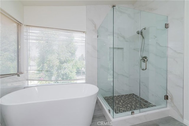 bathroom with a marble finish shower and a freestanding tub