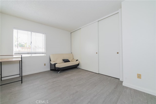 unfurnished room with a textured ceiling and light hardwood / wood-style floors