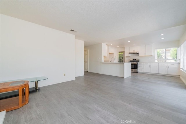 unfurnished living room with recessed lighting, a textured ceiling, visible vents, and light wood-type flooring